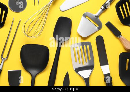 Different spatulas and other kitchen utensils on yellow background, flat lay Stock Photo