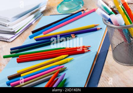 Multicolored pencils on table with papers and notebooks Stock Photo