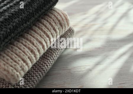 Stack of knitted scarfs on wooden table, space for text Stock Photo