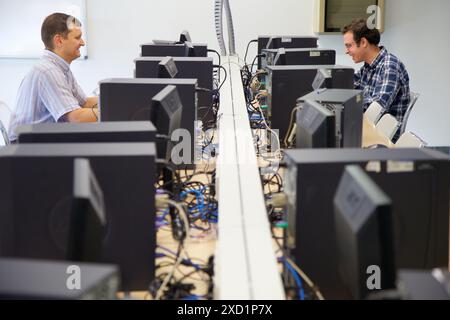 Two rows of people sitting at computers in an internet cafe, emailing ...