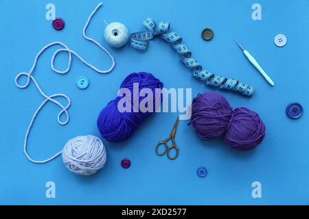 Yarn balls, measuring tape and scissors on blue background Stock Photo