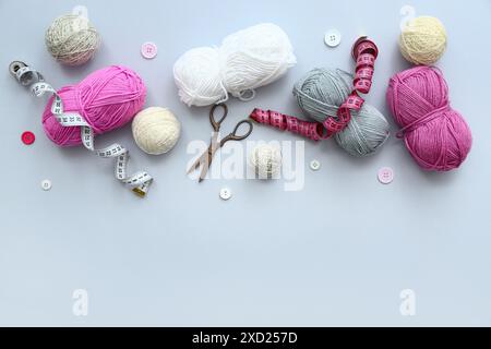 Yarn balls, measuring tapes and scissors on grey background Stock Photo