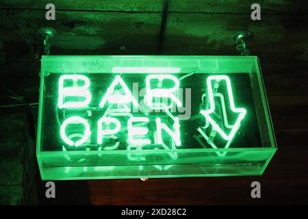 A green glowing neon sign indicating the bar is open. Stock Photo