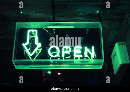 A green glowing neon sign indicating the bar is open. Stock Photo