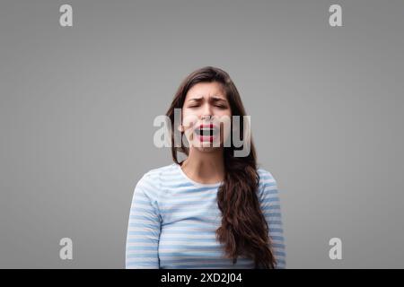 Young woman is experiencing intense sadness and despair, expressing her grief openly with tears streaming down her face Stock Photo