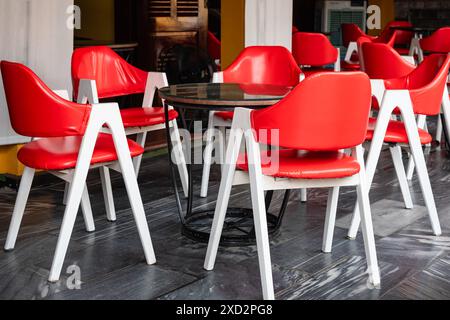 Street cafe with tables and red chairs outdoor. Empty dining table and chairs in a street restaurant terrace. Colorful table and chairs ready for a st Stock Photo