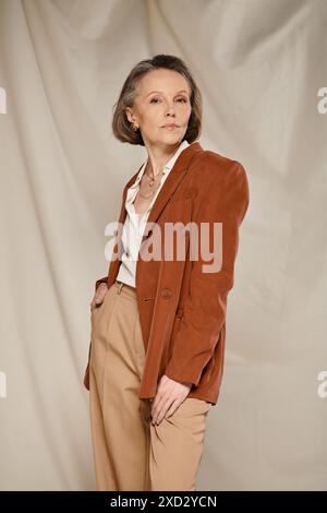 A mature woman in a brown blazer and tan pants, exuding confidence and style, engages in active poses. Stock Photo
