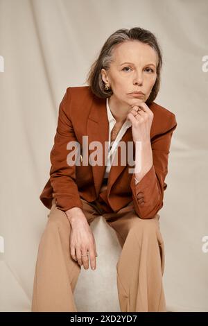 Stylish woman in brown blazer and tan pants gracefully poses and moves. Stock Photo