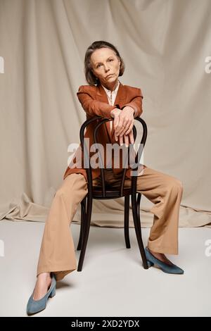 Mature woman in tan suit, seated gracefully on a chair, exuding ...