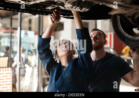 Mechanic, garage and working on car with motor training, maintenance engineer and teamwork at workplace. Repair shop, tools and mentor with woman Stock Photo