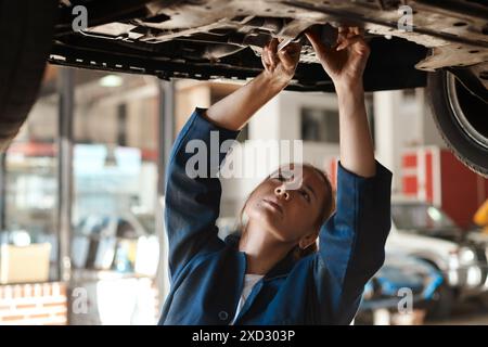 Woman, checking and tool for service with car in garage, inspection or maintenance on engine. Female mechanic, auto and wrench for problem with oil or Stock Photo