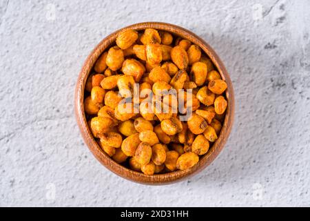 Roasted corn nuts with sauce in wooden bowl on white stone table Stock Photo