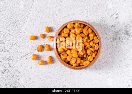 Roasted corn nuts with sauce in wooden bowl on white stone table Stock Photo
