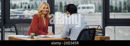 Mature woman engages in conversation with a man during job interview. Stock Photo