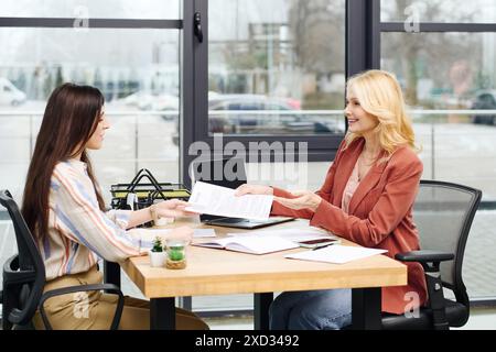 Two women engage in a discussion at a desk. Stock Photo