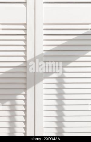 White Wooden Door With Louvres. Light And Shadows. Abstract Texture 