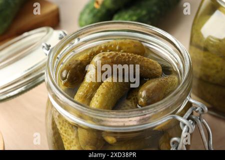 Pickled cucumbers in open jar on table, closeup Stock Photo