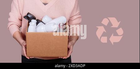 Woman holds cardboard box filled with plastic waste Stock Photo