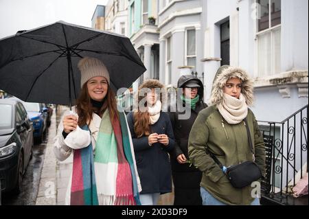 A diverse group of women strolling on a London street under an umbrella. Stock Photo