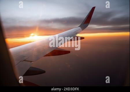A breathtaking view from a plane's window, capturing the airplane's wing against a vibrant sunset sky. Stock Photo