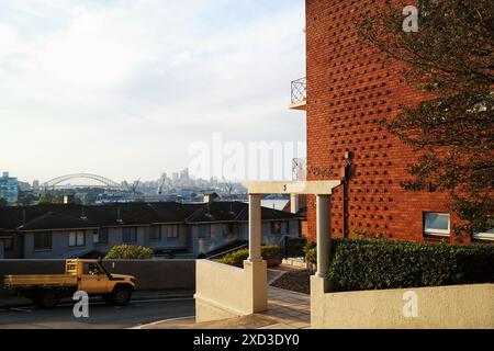 Looking past a red brick Mid Century Modern apartment block, Darling Point to Sydney Harbour and the arch of the Sydney Harbour Bridge late afternoon Stock Photo
