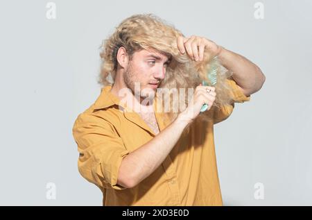 Hair loss blonde man with a comb and problem hair. Hairloss and hairs problems. Sad guy with damaged hair combing hairs. Alopecia, dandruff. Tangled, Stock Photo