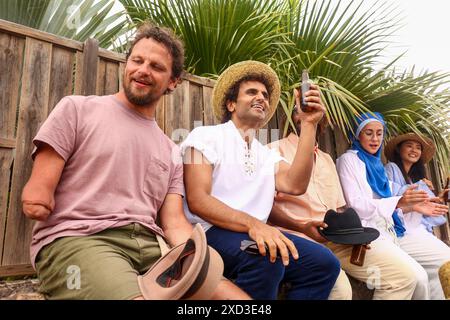 A joyful scene at a summer party showing a diverse group of friends enjoying drinks with a caucasian amputee man Stock Photo
