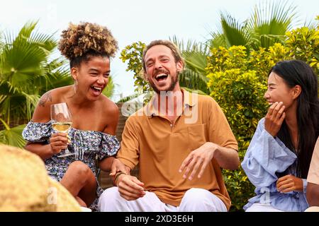 Multiethnic group of friends enjoying a rooftop party with laughter and drinks, capturing a moment of joy among a Caucasian man, African American woma Stock Photo