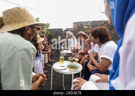 A lively group of friends engages in conversation while enjoying a BBQ and music outdoors. Several are looking at each other, and some look away, crea Stock Photo