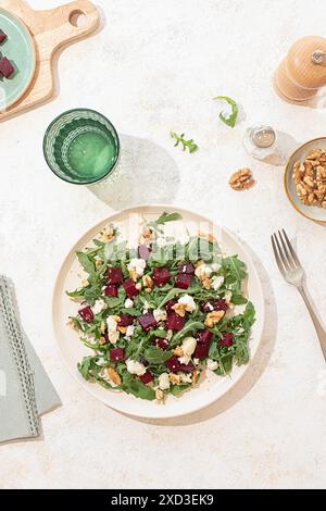 A fresh arugula salad with goat cheese, walnuts, and beetroot on a beige plate. Natural light highlights the vibrant colors and textures, creating a f Stock Photo