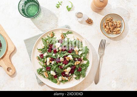 A beautifully styled arugula salad with goat cheese, walnuts, and beetroot on a light beige plate. Natural light highlights the vibrant colors and tex Stock Photo
