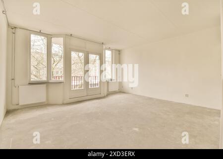Light-filled empty room featuring large windows and a balcony view. The neutral walls and concrete floor offer a blank canvas for personalized design, Stock Photo