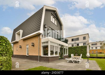 A house with a lawn in the front and two chairs on the outside, all facing towards each other buildings Stock Photo
