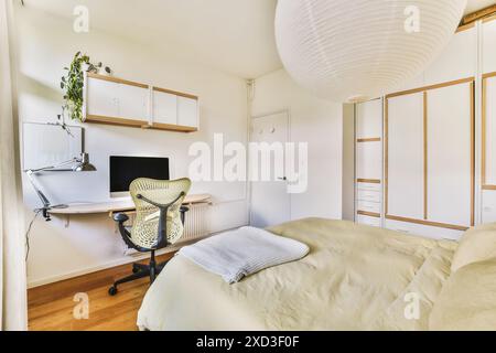 A minimalist bedroom featuring a stylish home office corner with nature illustrations, at Spilbergenstraat 21 Stock Photo