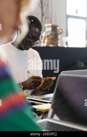 A young multiethnic couple enjoys smart working at home, collaborating with nature illustrations on creative tasks Stock Photo