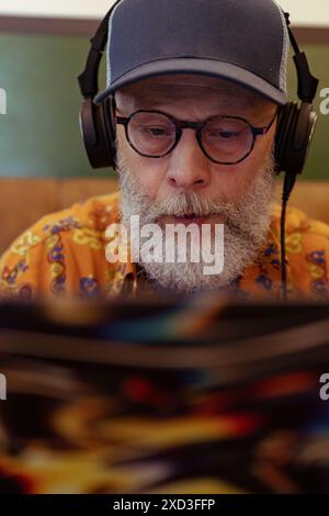 Senior man with beard and headphones working remotely on laptop, showcasing modern lifestyle Stock Photo