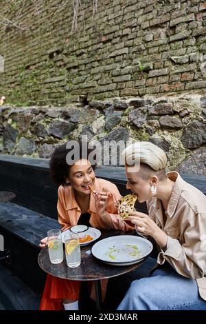 Two diverse, beautiful lesbians enjoy a meal at a cozy cafe. Stock Photo