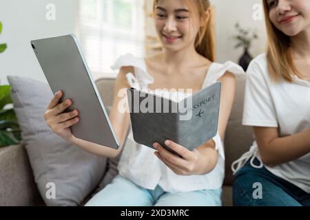 Young Women Planning Travel with Tablet and Passport, Preparing for an Exciting Adventure Stock Photo