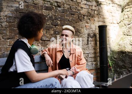 Two women sitting on a bench, engaged in conversation. Stock Photo