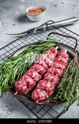 Raw Turkish Urfa kebab decorated with herbs, spices and meat fork. Gray background. Top view. Stock Photo