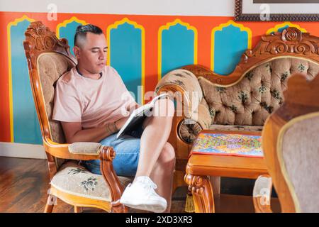 Latin Man Reading Book in Vibrant Traditional Living Room Stock Photo