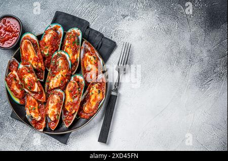 Large green mussels cooked in tomato sauce with garlic, parsley and lemon. White background. Top view. Copy space. Stock Photo