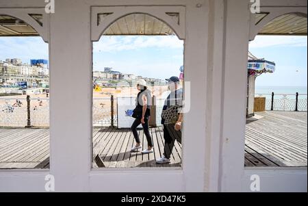 Brighton UK 20th June 2024 - Visitors enjoy a walk on Brighton Palace Pier on a warm sunny day along the South Coast as hot weather is forecast for Britain over the next week . : Credit Simon Dack / Alamy Live News Stock Photo