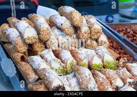 Sicilian Cannolo, a fried pastry filled with ricotta and garnished with chopped nuts  on display on a market stall Stock Photo