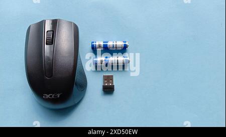 Photo of a wireless mouse with battery and usb next to it on a blue background Stock Photo