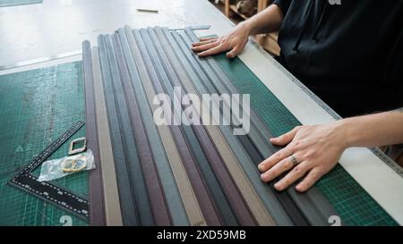 A tanner makes leather belts in a workshop. Close-up of a man's hands. Stock Photo