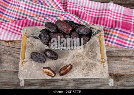 Large size Jerusalem Date fruit. Close up shot of date fruit on marble tray in silver bowl on wooden table background. Dried date fruit is healthy as Stock Photo