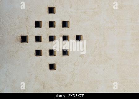 Spaced out small square glass bricks in square pattern through stucco coated wall Stock Photo
