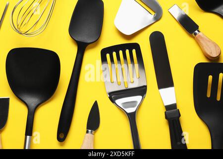 Different spatulas and other kitchen utensils on yellow background, flat lay Stock Photo