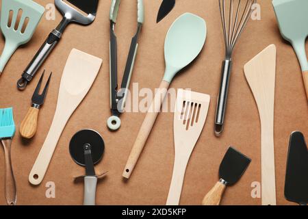 Different spatulas and other kitchen utensils on brown background, flat lay Stock Photo